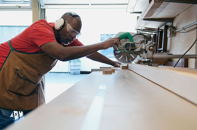A man using a circular saw at work while using proper protective equipment