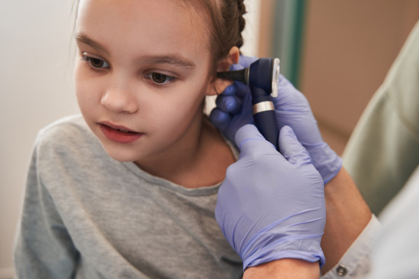 A child receiving an ear exam from a hearing specialist