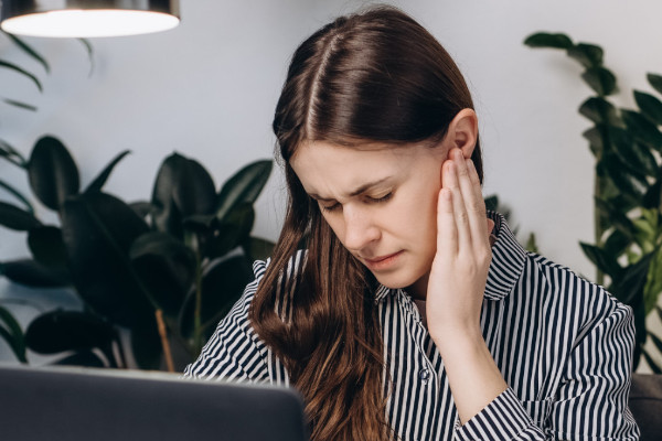 A woman rubs her ear as if it were causing her irritation