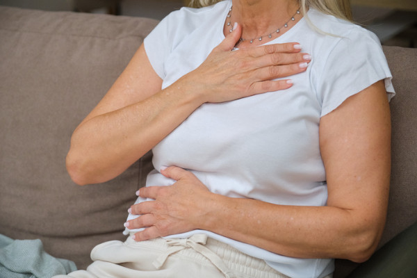 a woman holding her stomach and chest due to acid reflux