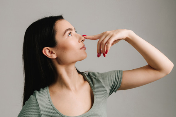 A woman holding her finger to her nose