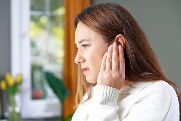 A woman rubs her ear as if it were causing her irritation