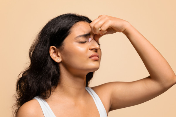A woman holding the top of her nose