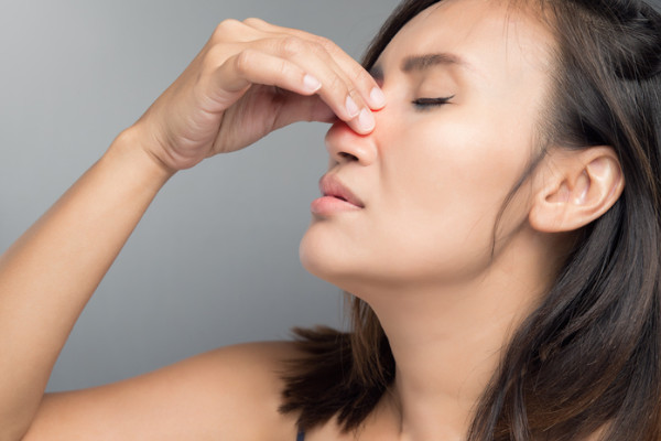 A woman holding her nose in discomfort