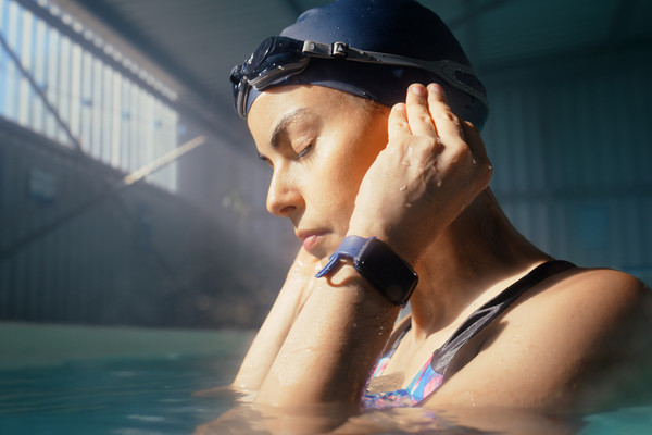 A woman in swimmer's attire in a pool holding her ears.