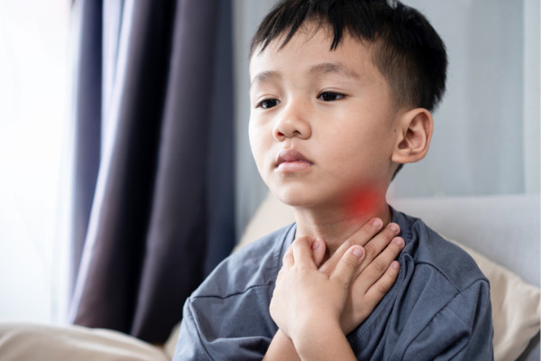A child rubbing his sore throat
