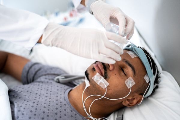 alt="Doctor preparing patient in bed for polysomnography (sleep study)"