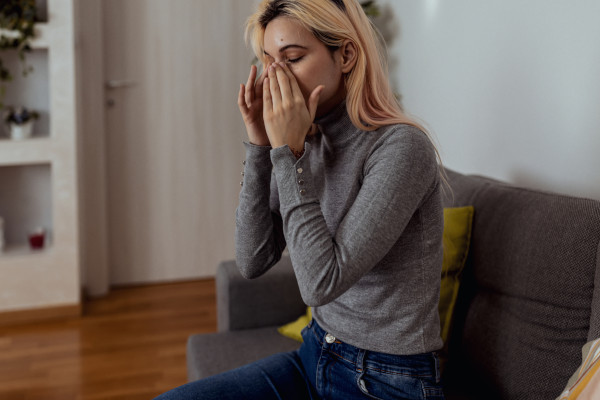 A woman rubbing her face, suffering from chronic sinusitis