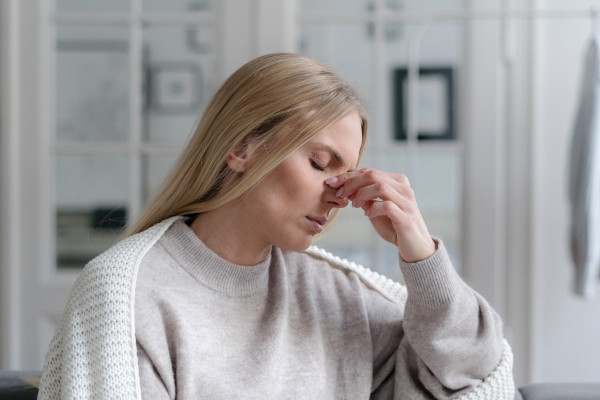 A woman on the couch in a robe is experiencing sinus pain